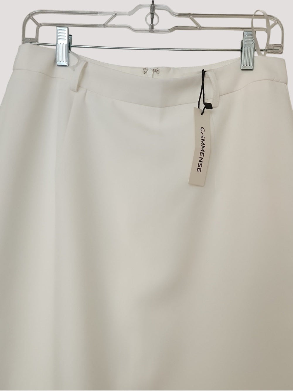 Minimistcloset Commense cream high-waist pencil skirt with a minimalist design hanging on a metal hanger.